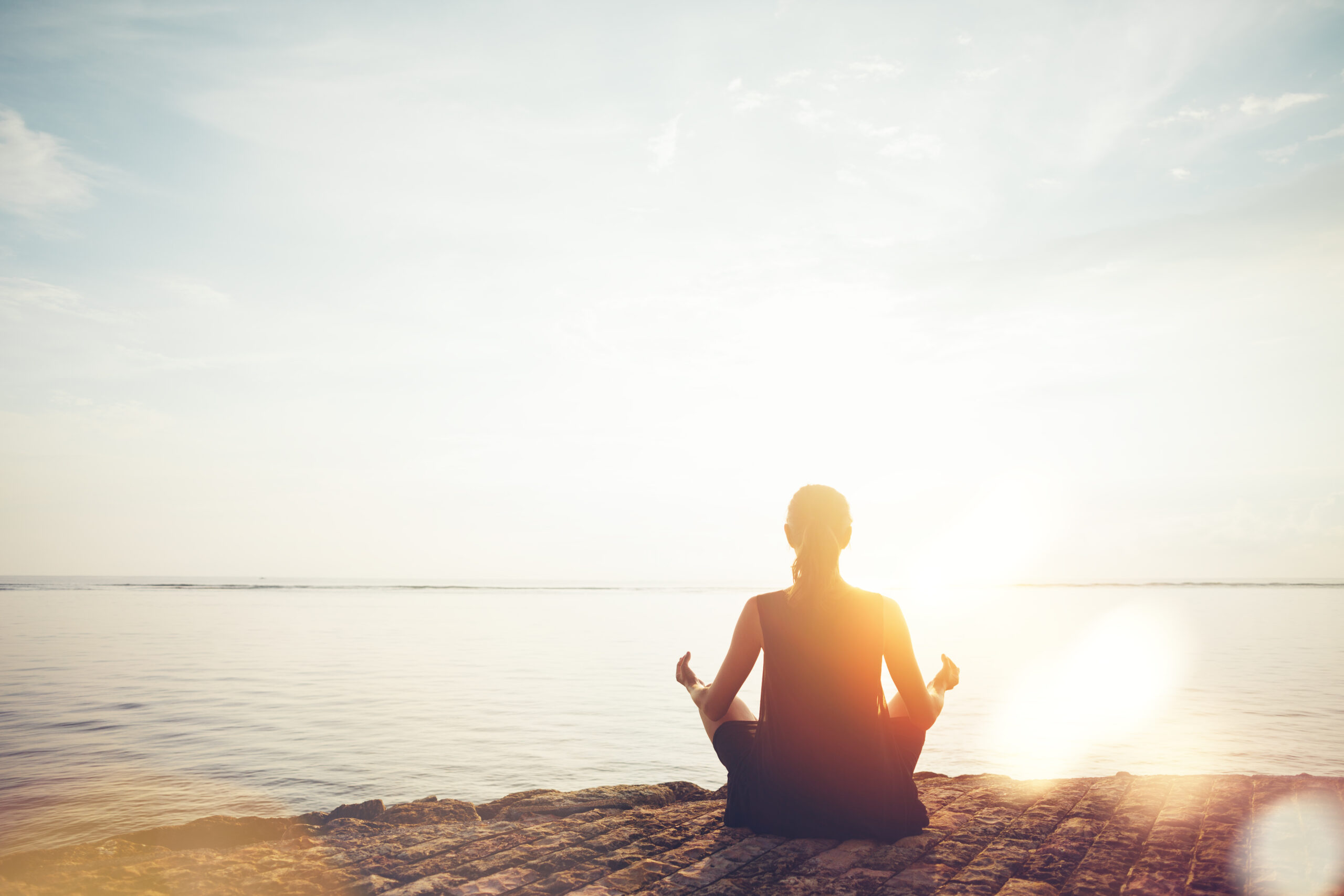 Young woman doing meditation practice on the beach.