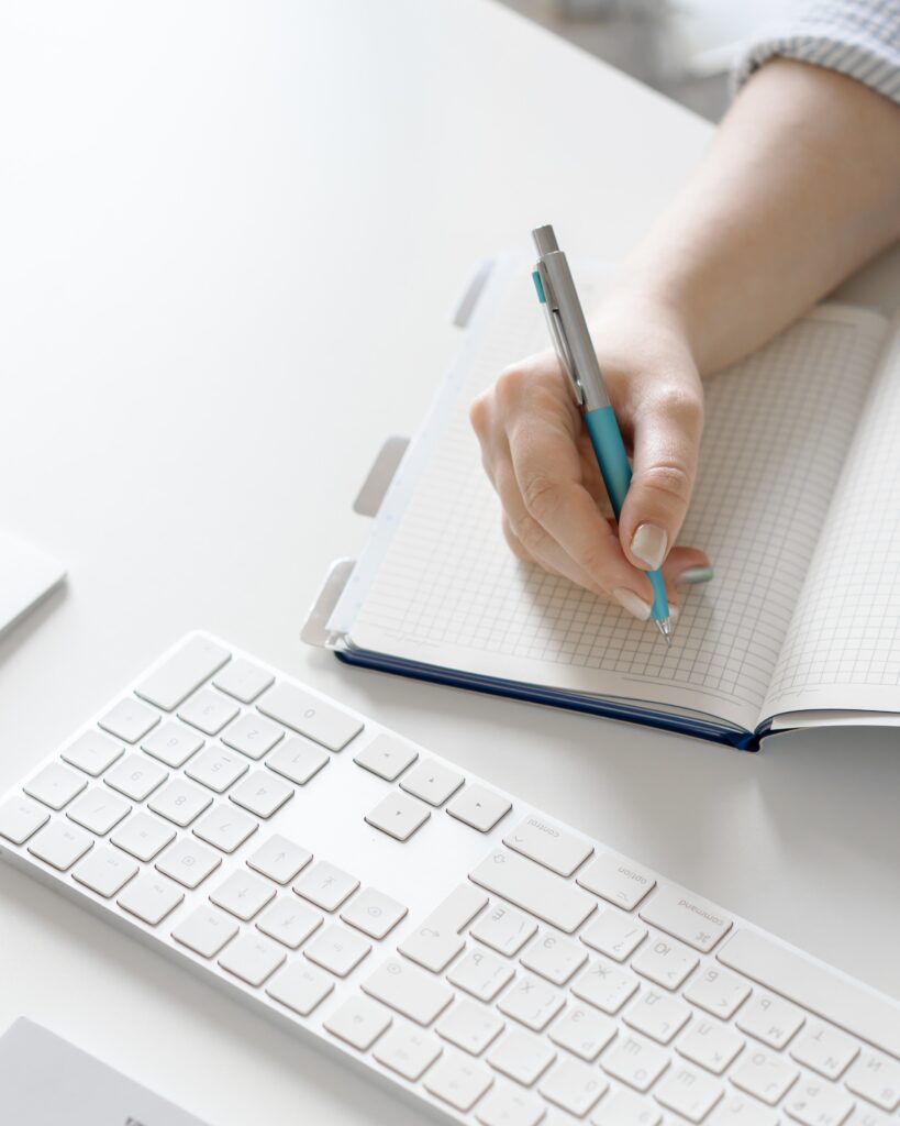 A person taking notes while working on their computer