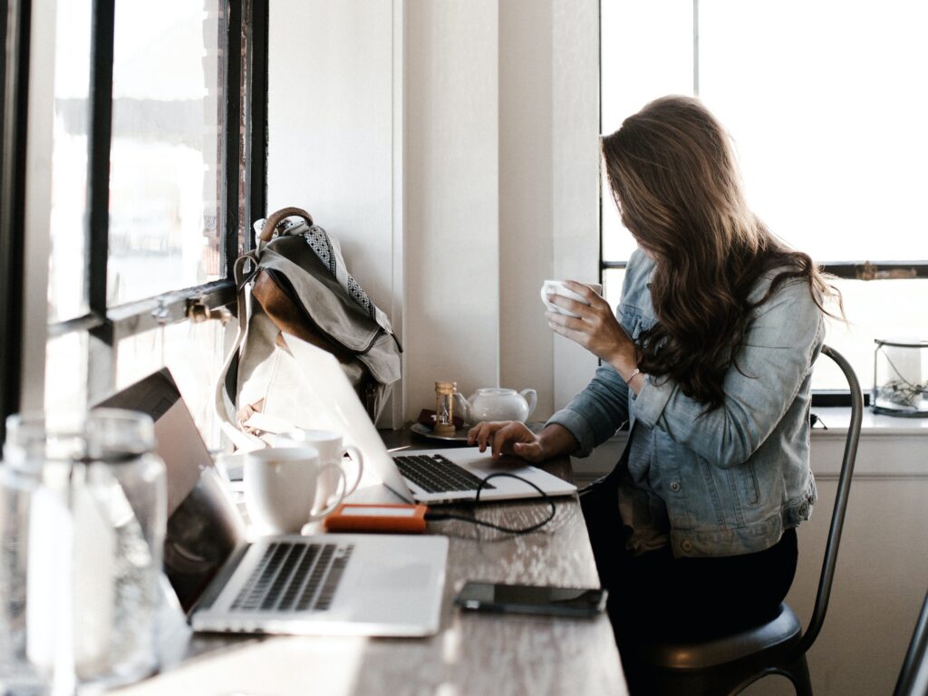 A woman working at her computer setting goals while holding her coffee mug.