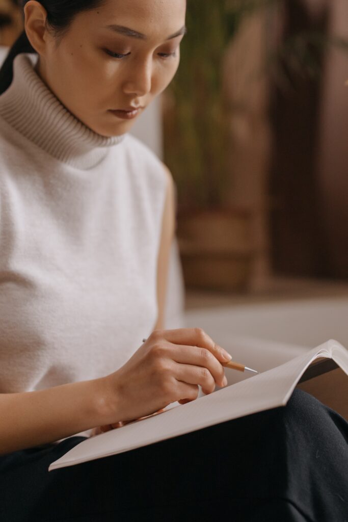 A woman writing in her journal or planner with a pen