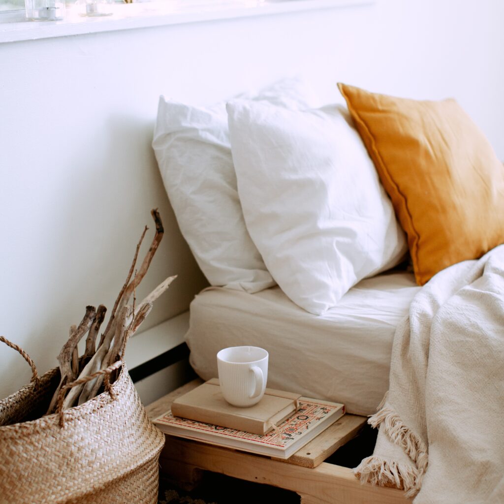 Pillows on a bed with a coffee cup and books