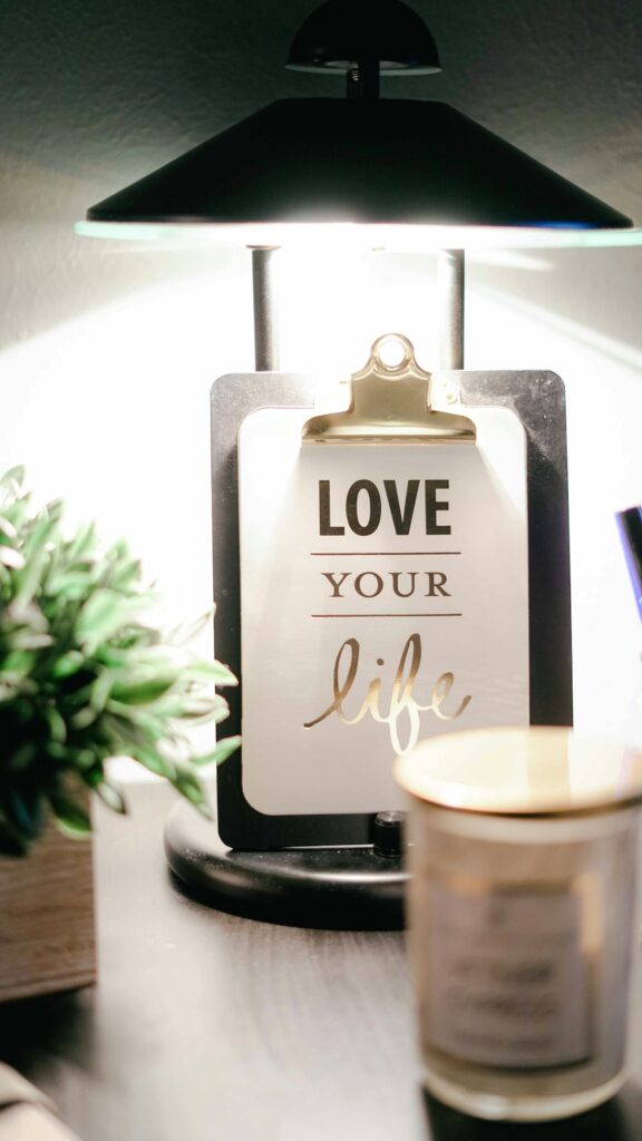 Love Your Life and plan meaningful new year's resolutions.  A clipboard sitting in front of a candle, under a lamp.