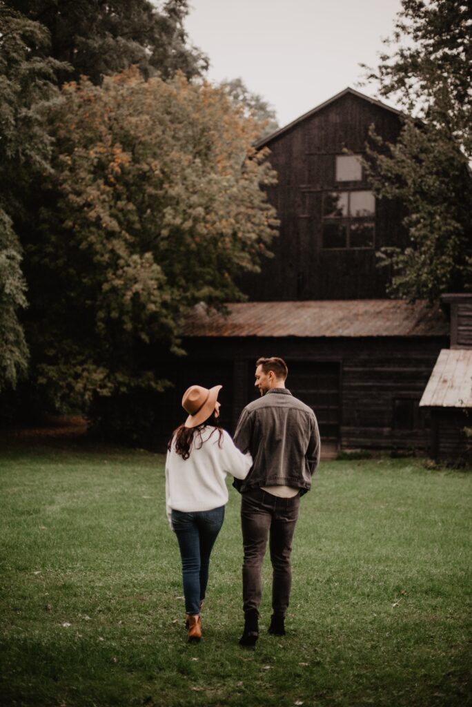 A man and woman walking together in a grassy area towards a house