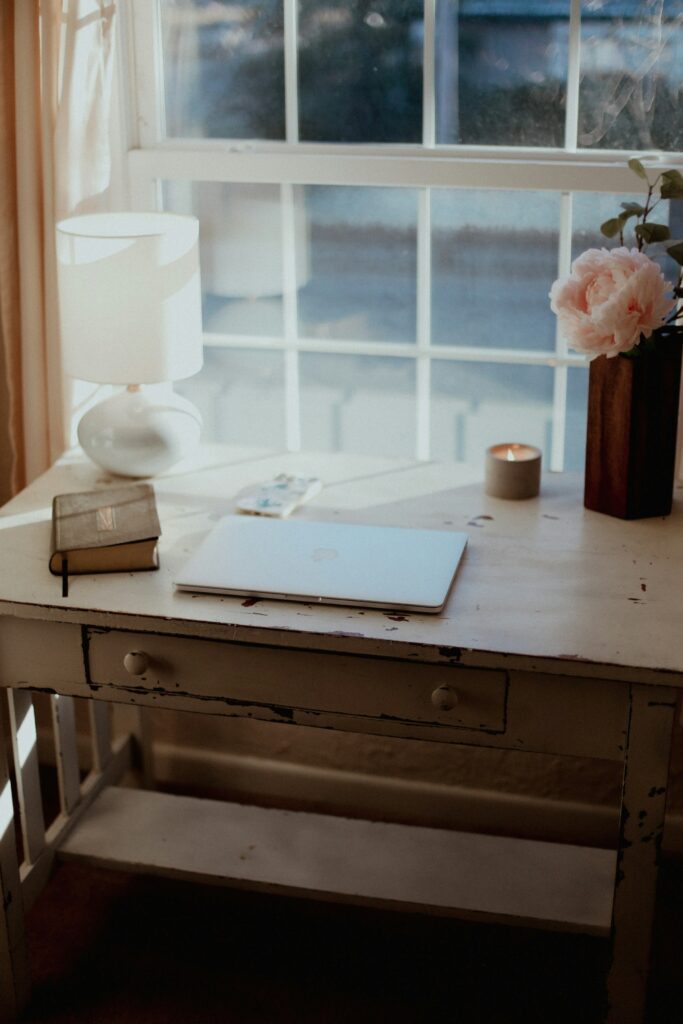 A desk set up ready for a mid-year goals review with a laptop, and book, and a candle.
