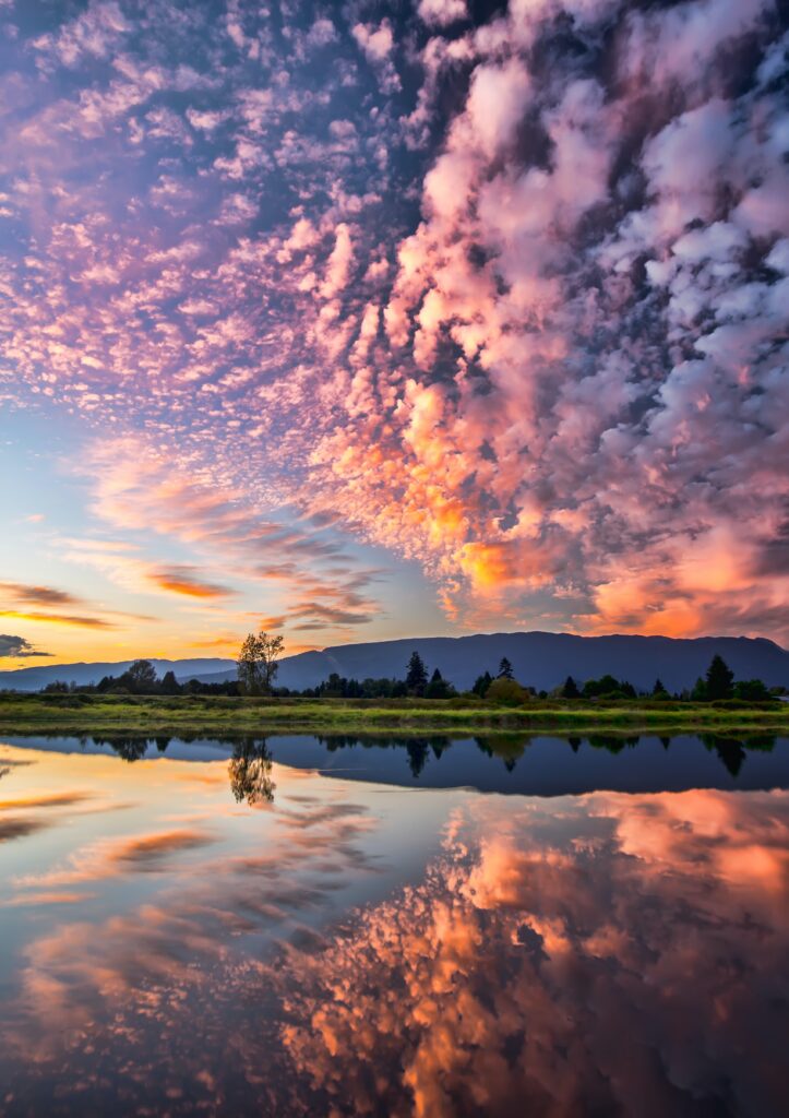 A beautiful sunrise with orange and purple clouds over a lake.